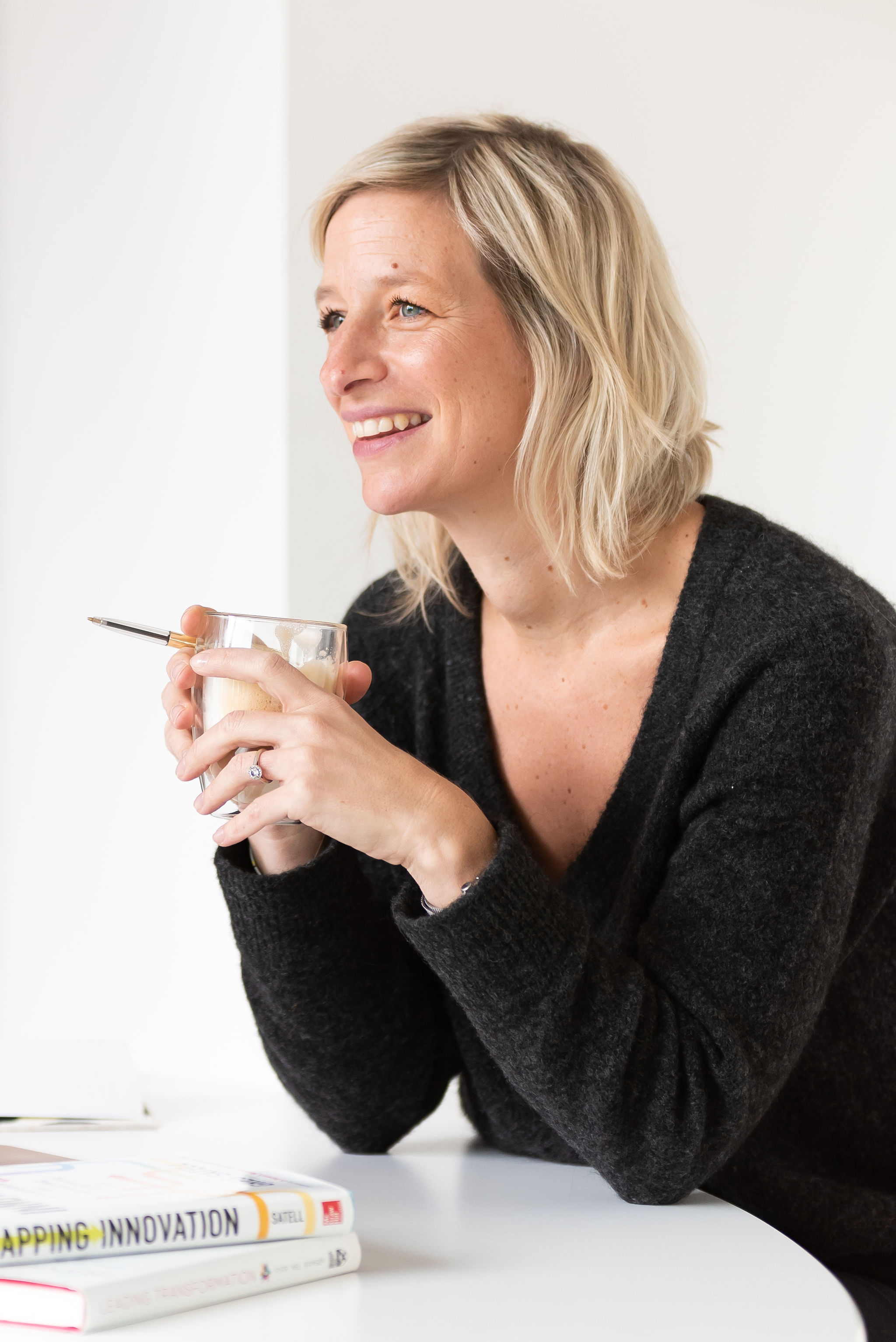 Elke van VOLT7, lachend met een koffie aan tafel